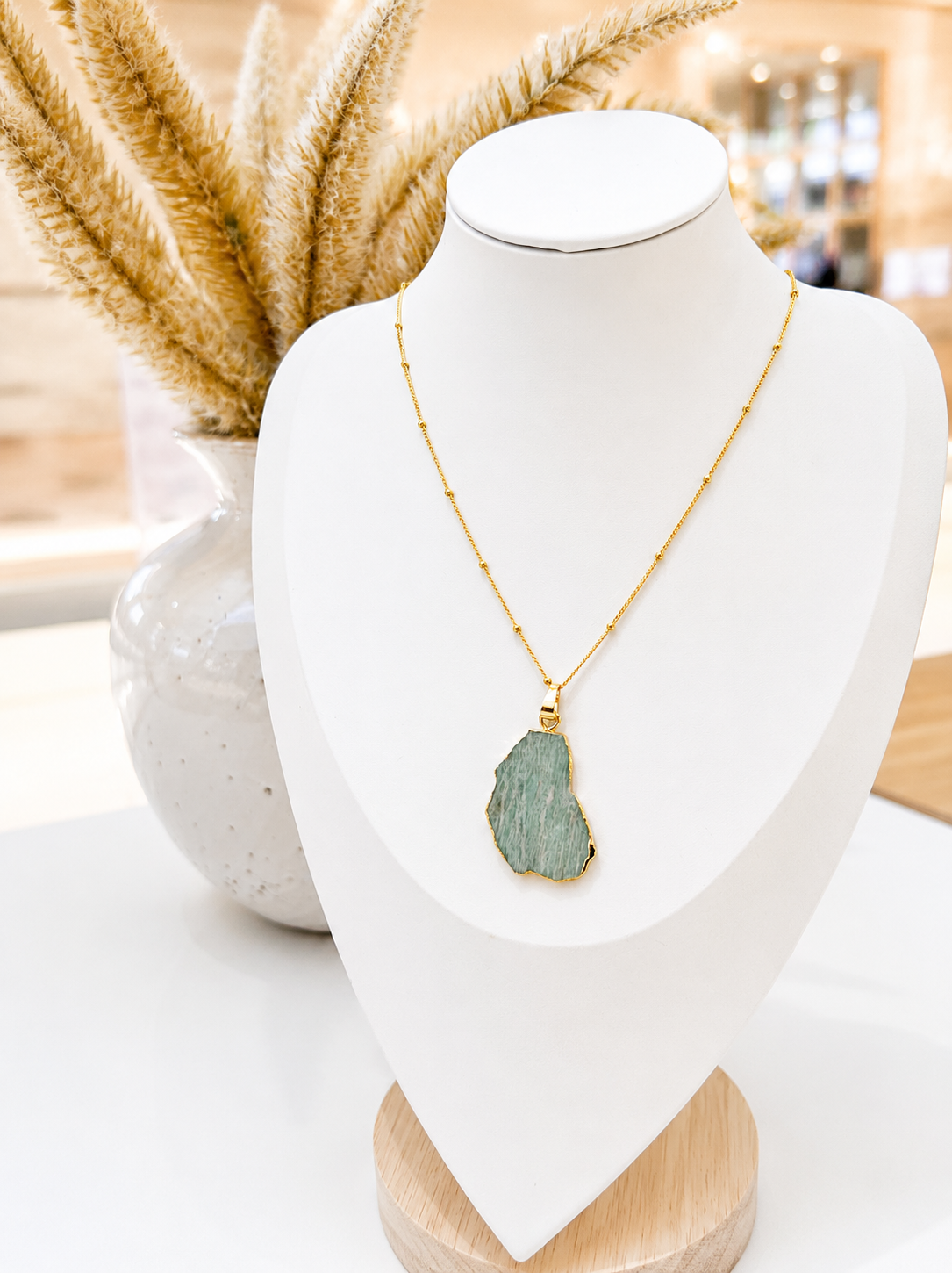 
                  
                    Necklace with a amazonite pendant on a white mannequin bust against a neutral background
                  
                
