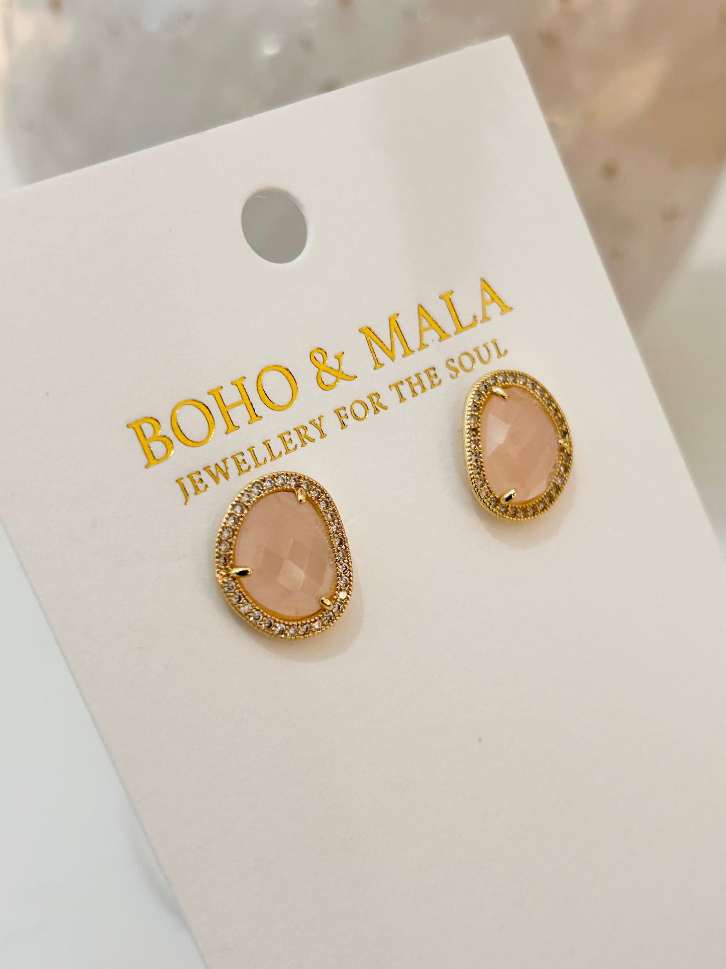 
                  
                    Pair of gold and pink earrings on a BOHO & MALA branded card.
                  
                