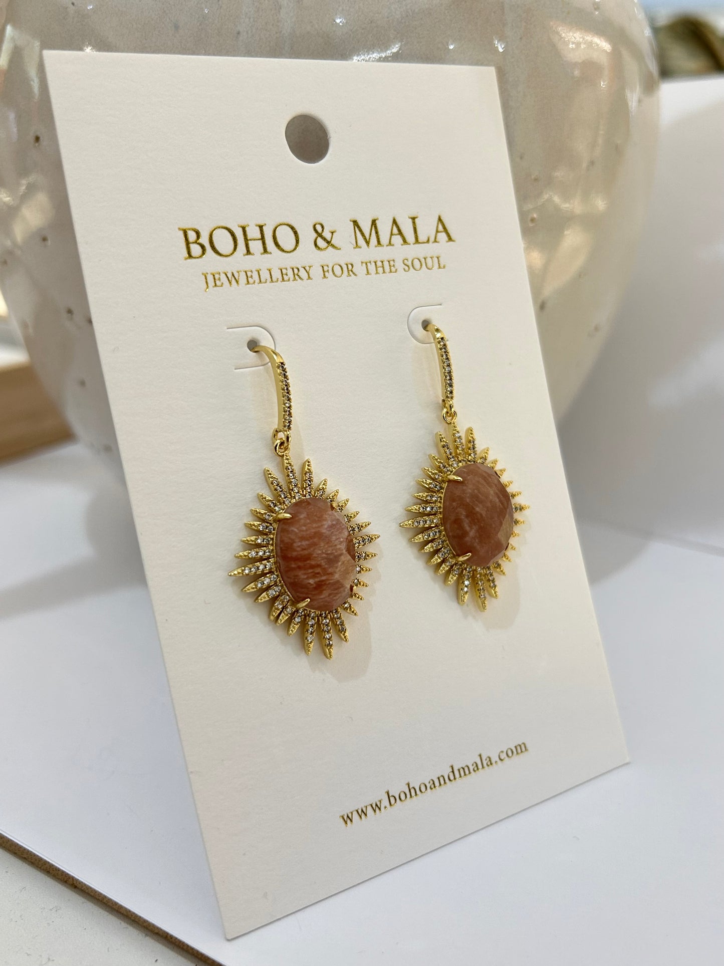 
                  
                    Pair of gold earrings on a BOHO & MALA branded card.
                  
                