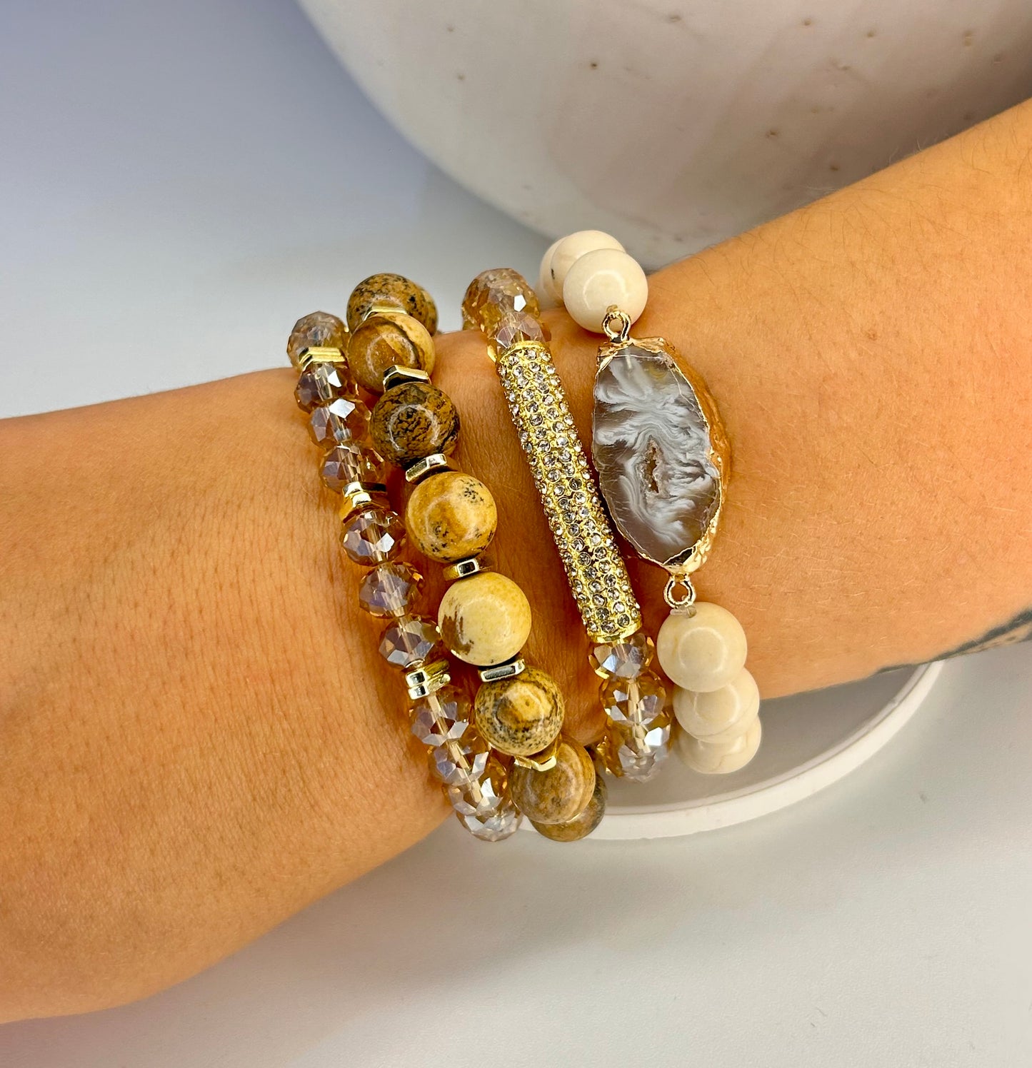 Stack of beaded desert jasper mixed bracelets on a wrist with a neutral background
