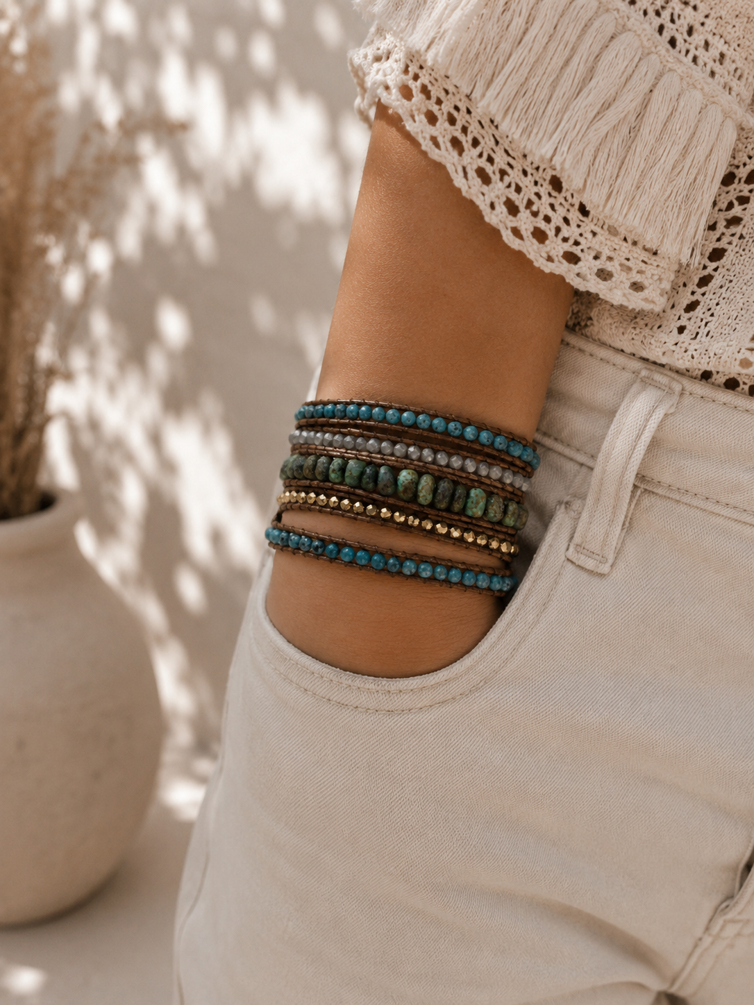 
                  
                    Person wearing turquoise wrap beaded bracelets on a neutral background
                  
                