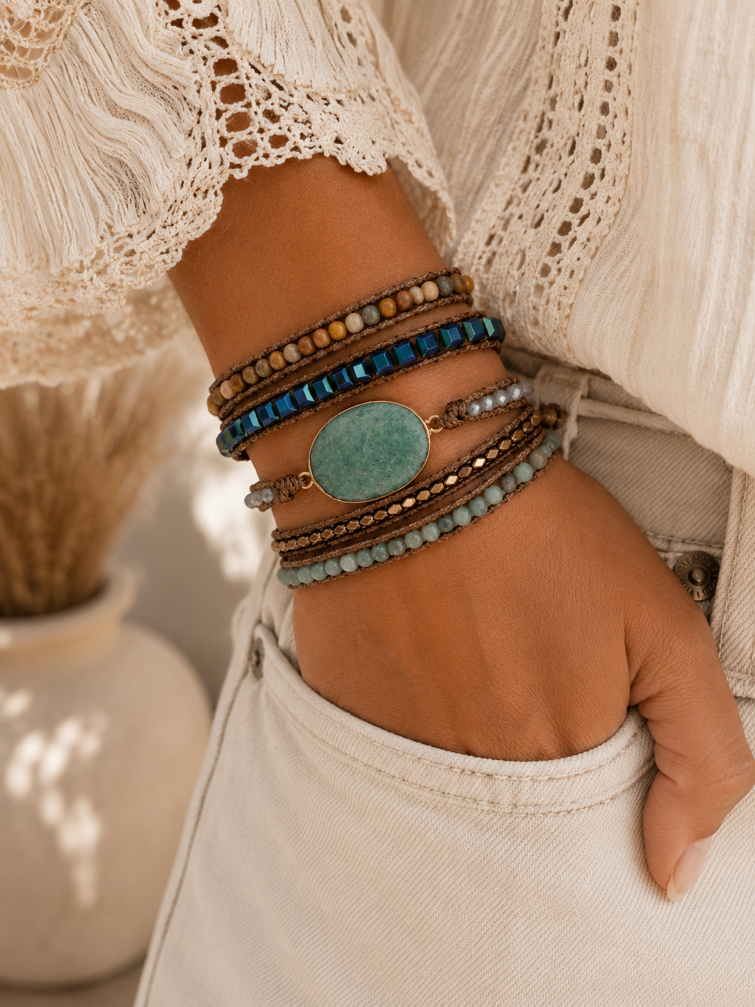 
                  
                    Close-up of a hand wearing amazonite wrap bracelets with a blurred natural background
                  
                