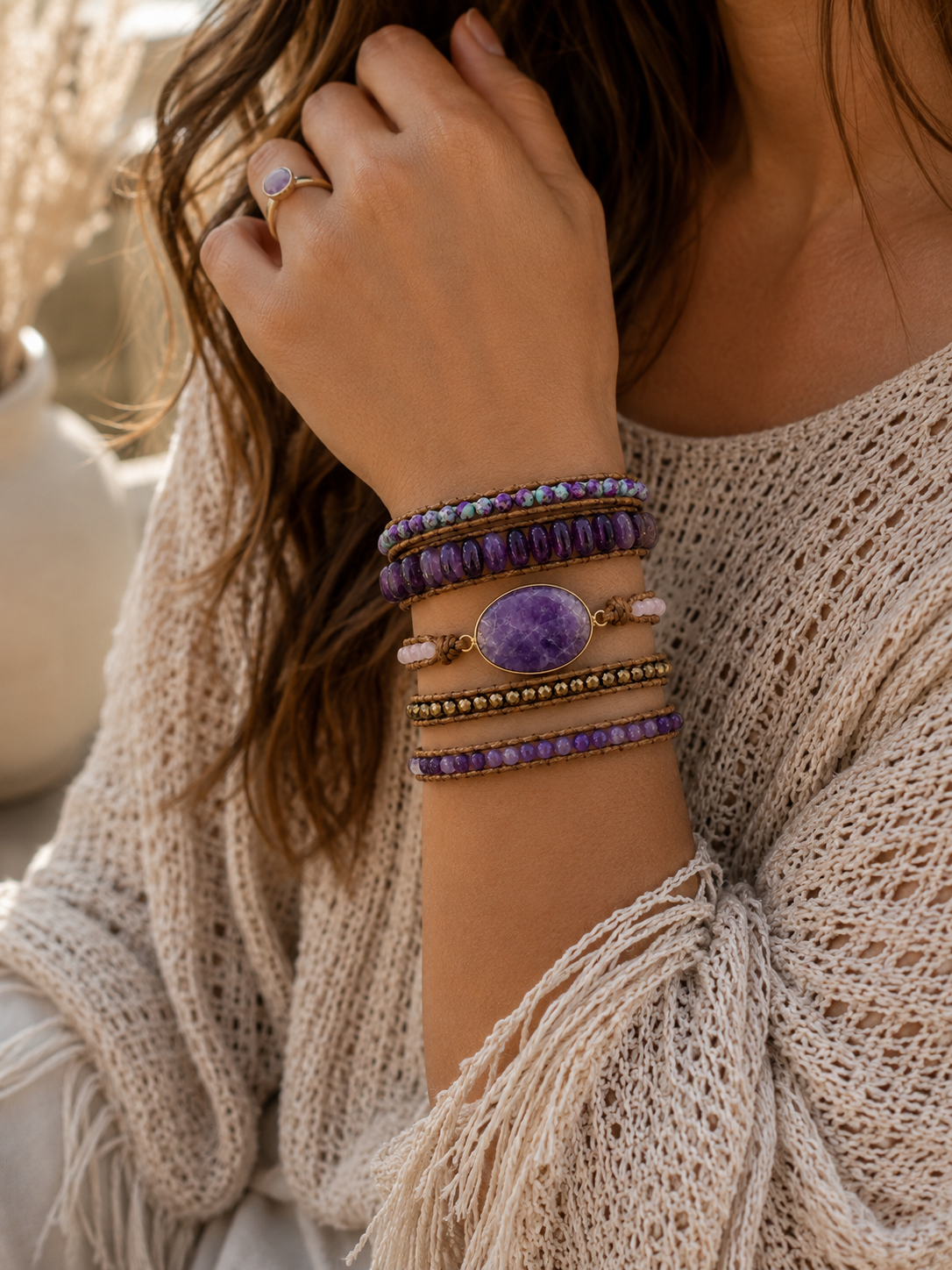 
                  
                    Close-up of a person wearing a wrap amethyst beaded bracelets on a blurred outdoor background
                  
                