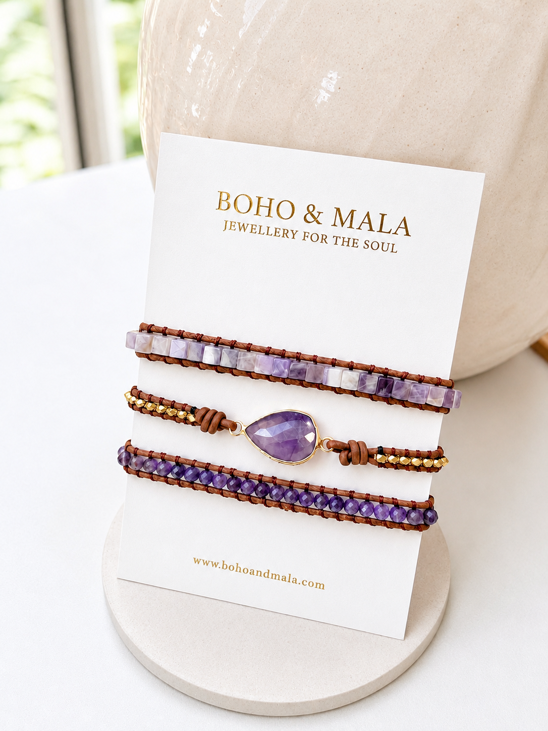 Wrap amethyst beaded bracelets with an amethyst charm on a 'Boho & Mala' card.