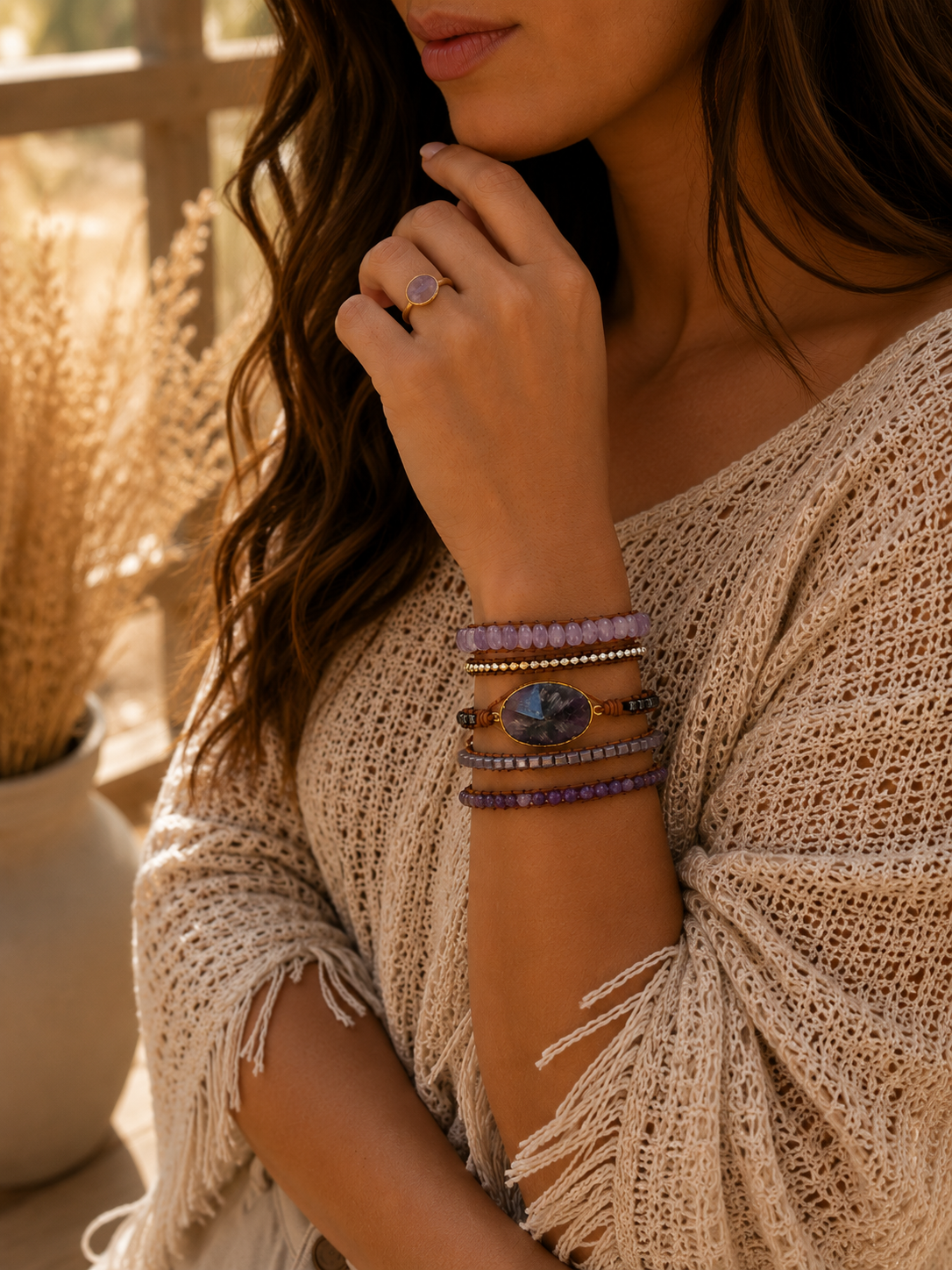 
                  
                    Close-up of a woman's arm wearing amethyst wrap bracelets with a neutral background
                  
                