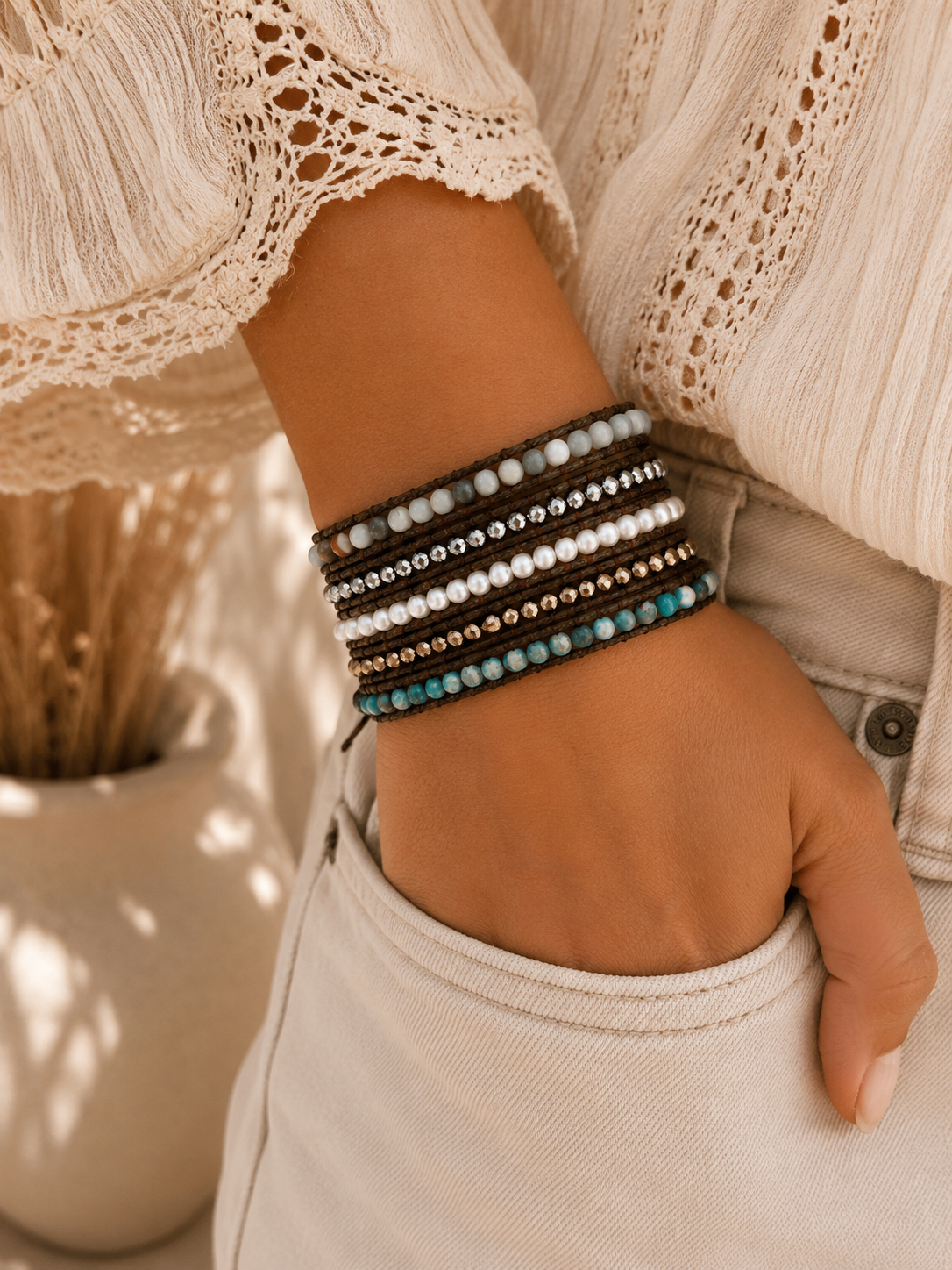 
                  
                    Close-up of a wrist wearing fresh water pearl wrap beaded bracelets with a blurred indoor background.
                  
                