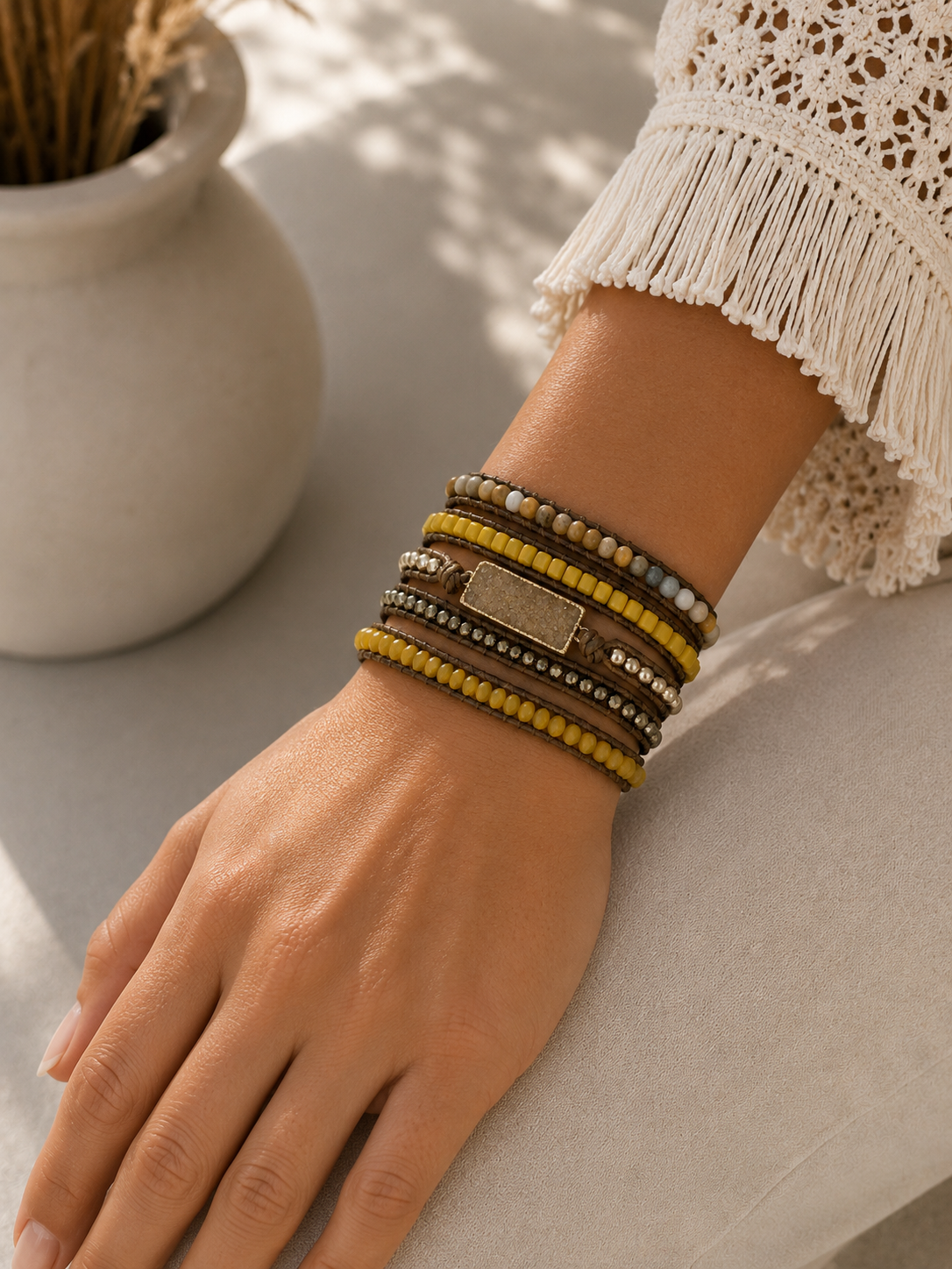 
                  
                    Close-up of a wrist wearing mixed golden druzy wrap bracelets with a neutral background
                  
                
