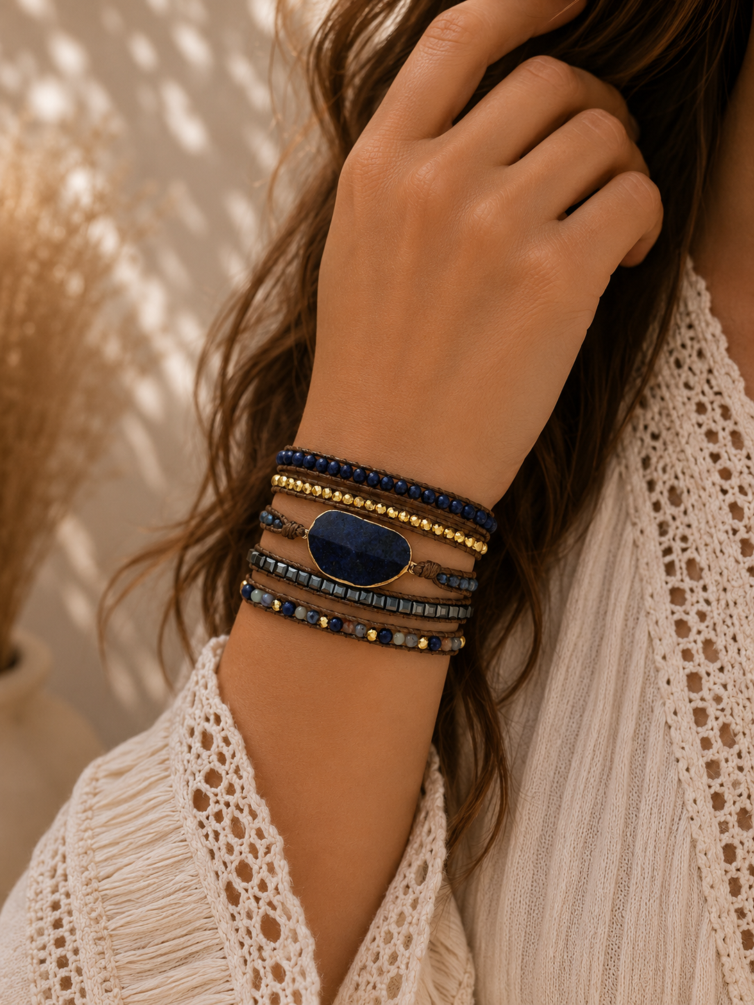 
                  
                    Close-up of a hand wearing lapis lazuli stones on a  beaded wrap bracelets on a blurred background
                  
                