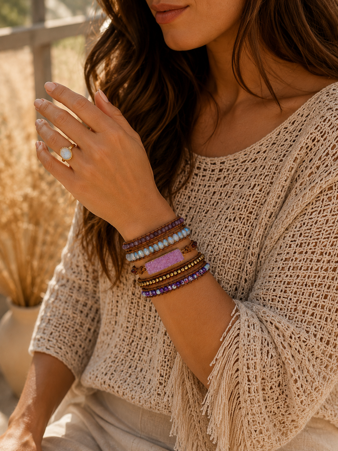 
                  
                    Woman wearing a beige crochet top with fringe details, holding a ring, and wearing amethyst wrap bracelets.
                  
                