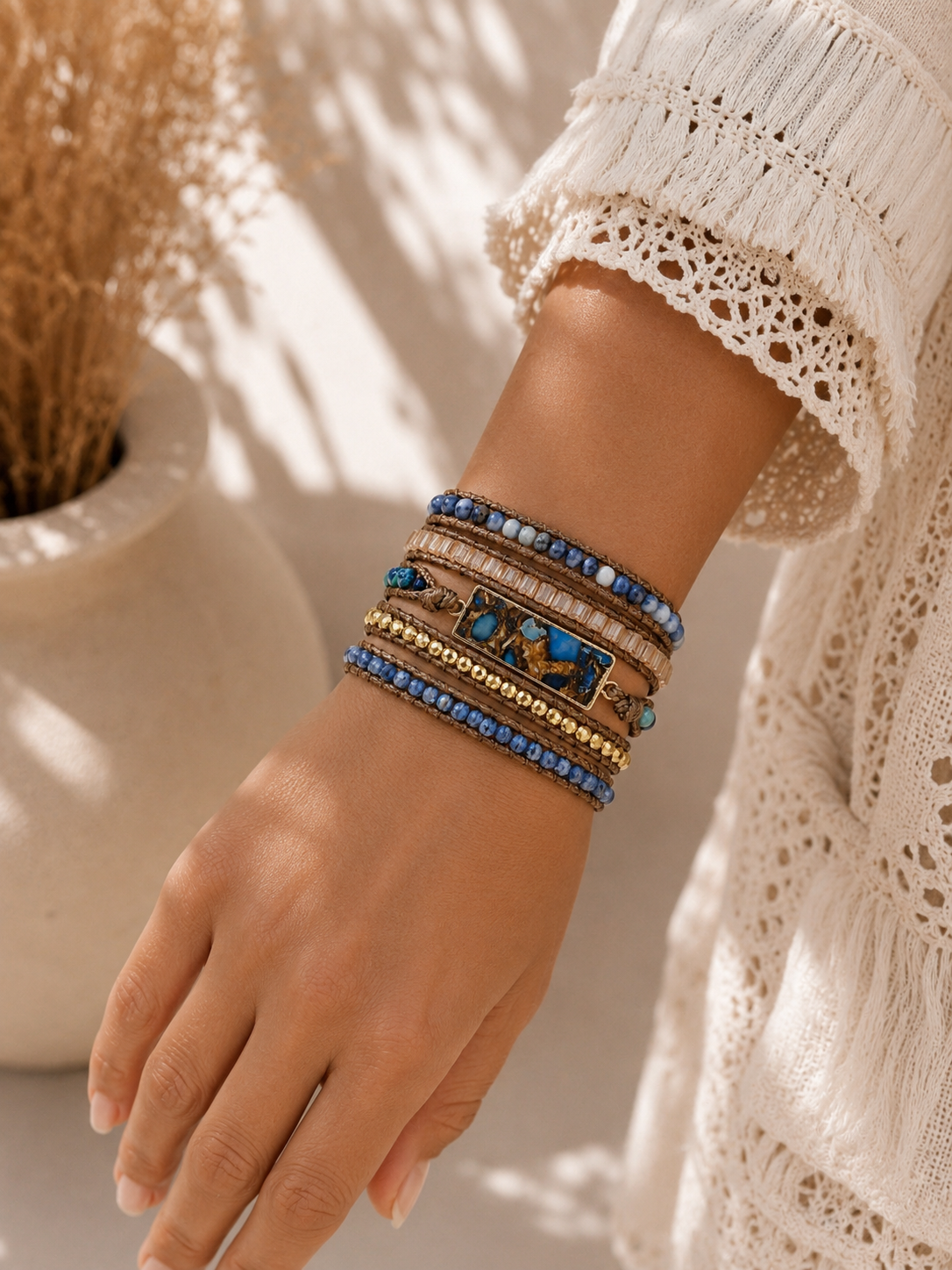 
                  
                    Hand wearing a sodalite wrap bracelet with blue stones against a neutral background
                  
                