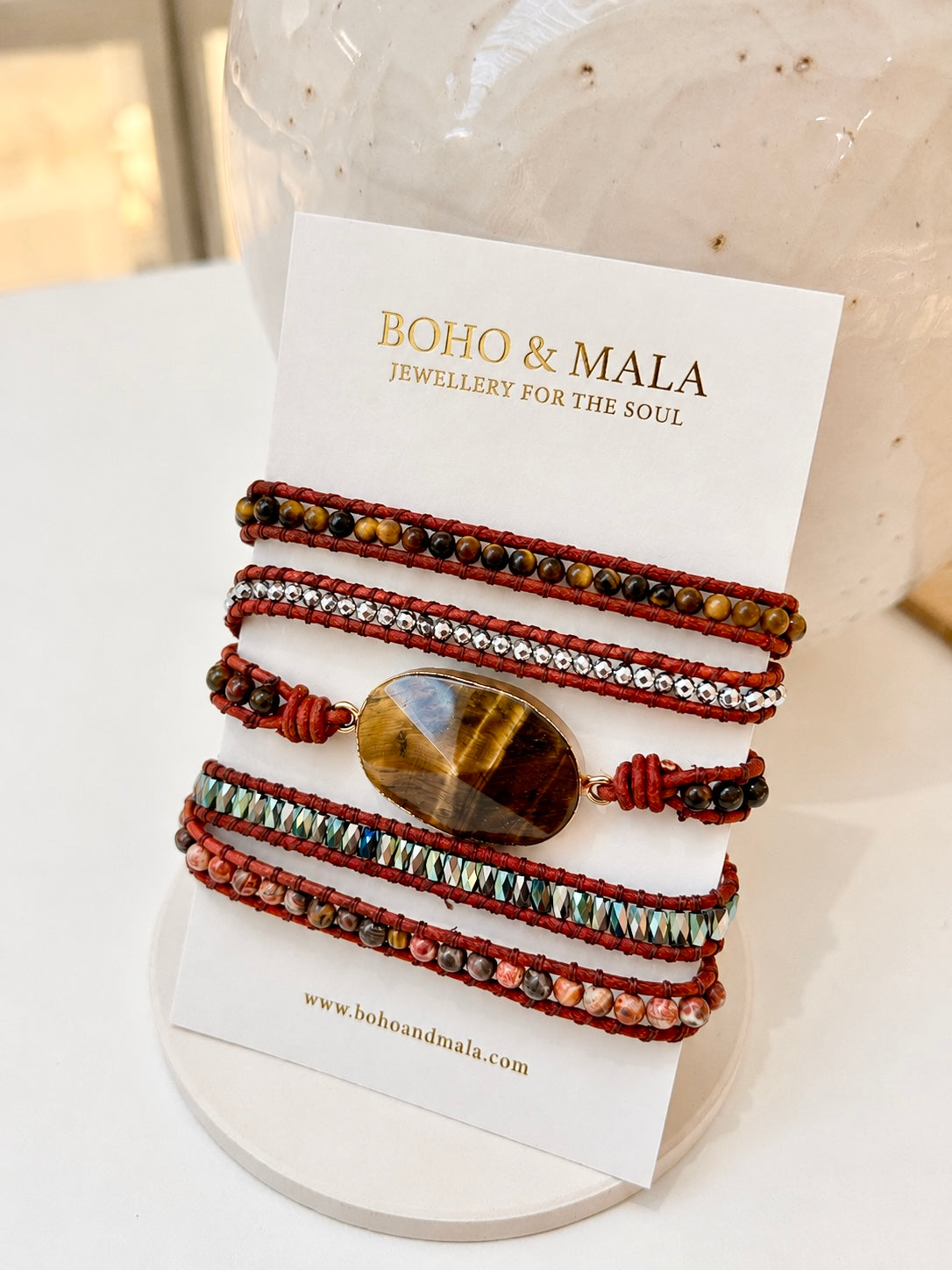 A set of four bohemian-style natural beaded bracelets with a large tiger's eye stone, displayed on a white card labeled 'BOHO & MALA'.