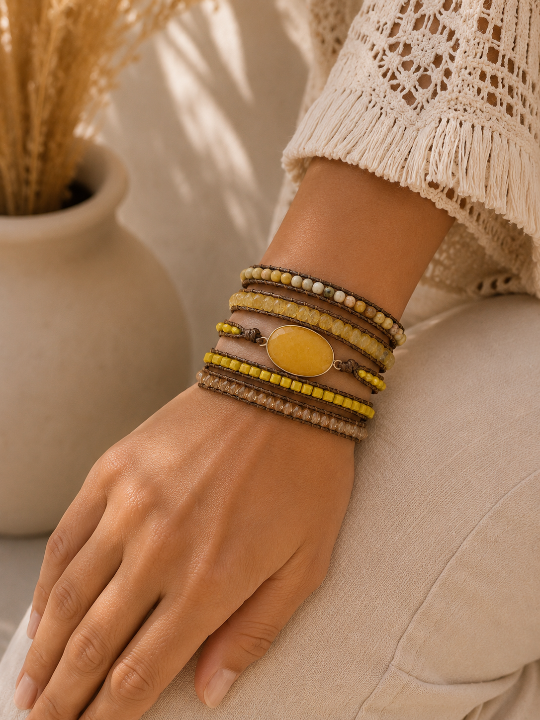 
                  
                    Hand wearing yellow jade mixed wrap bracelets with a neutral background
                  
                