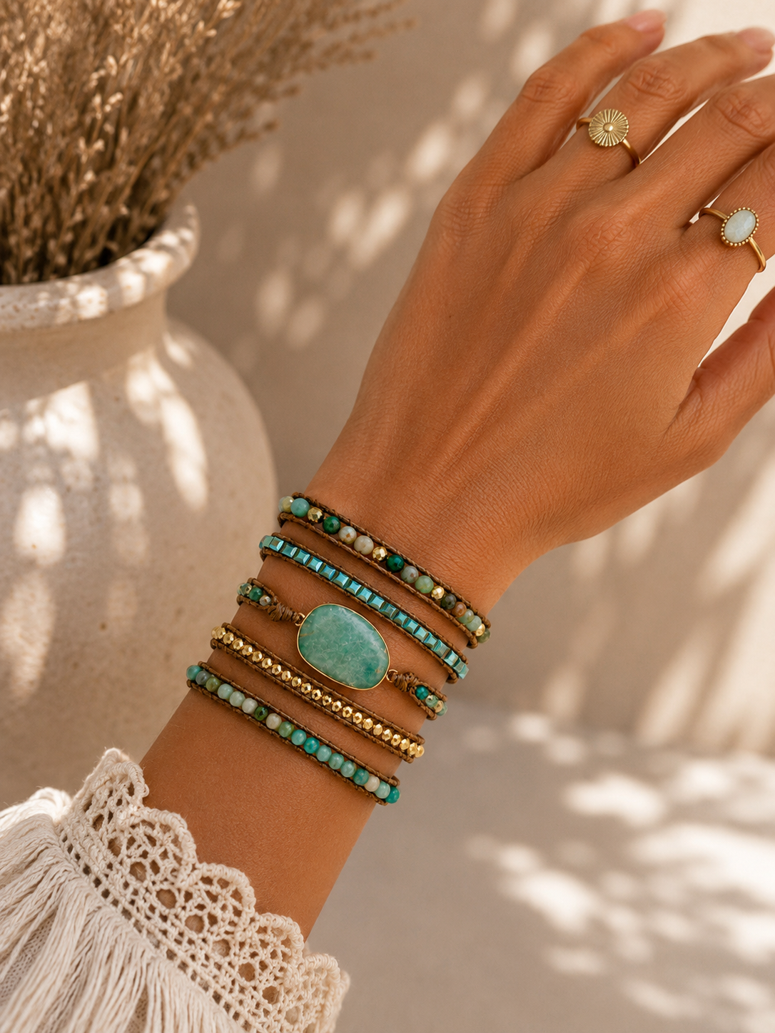 
                  
                    Hand wearing multiple amazonite wrap bracelets with turquoise stones against a neutral background
                  
                