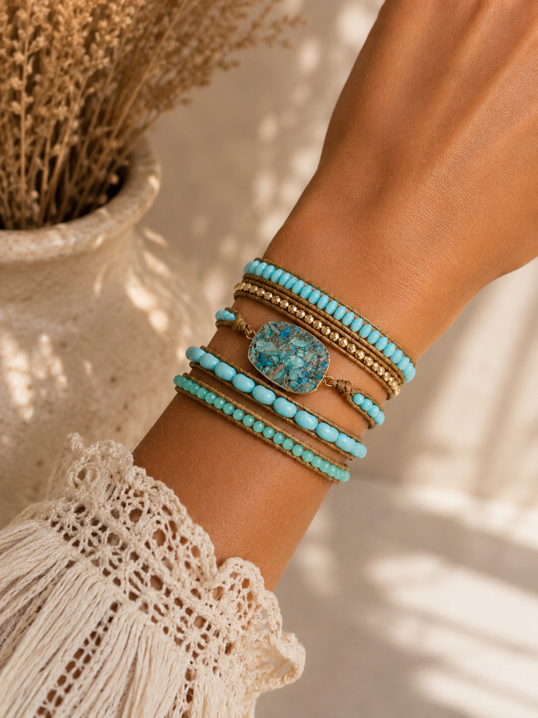 
                  
                    Close-up of a wrist wearing turquoise and amazonite turquoise beaded bracelets with a neutral background
                  
                