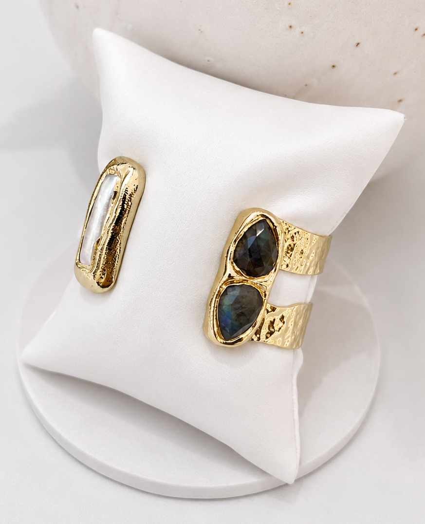 
                  
                    Gold double cuff bangle with labradorite stones with freshwater pearls on a white stand against a neutral background
                  
                