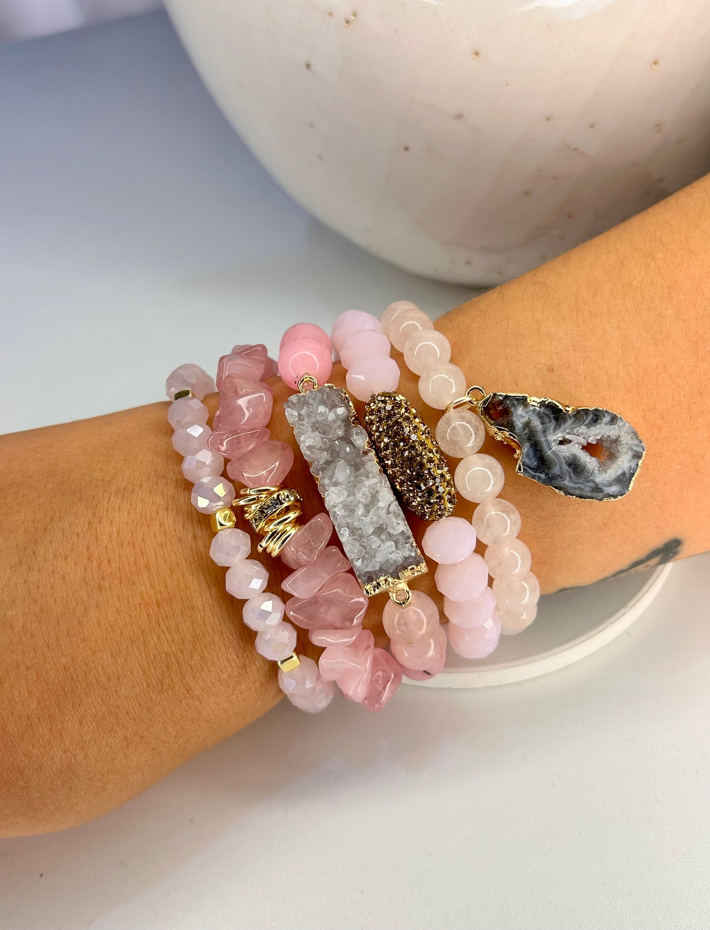 Stack of pink rose quartz beaded bracelets on a wrist with a blurred background
